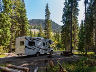 Beautiful campsite in the mountains with an RV and wooden bench.